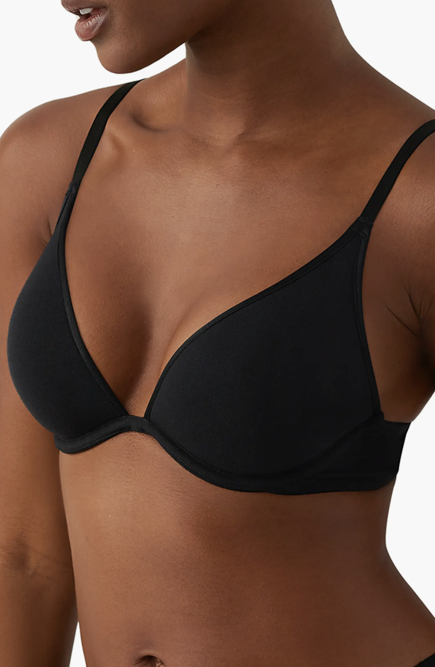 The torso of a woman wearing a minimalist black plunging bra.